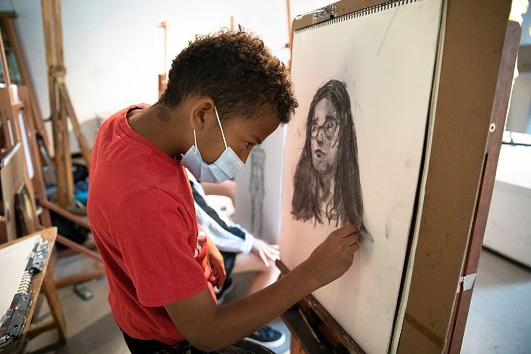 Boy drawing woman with glasses