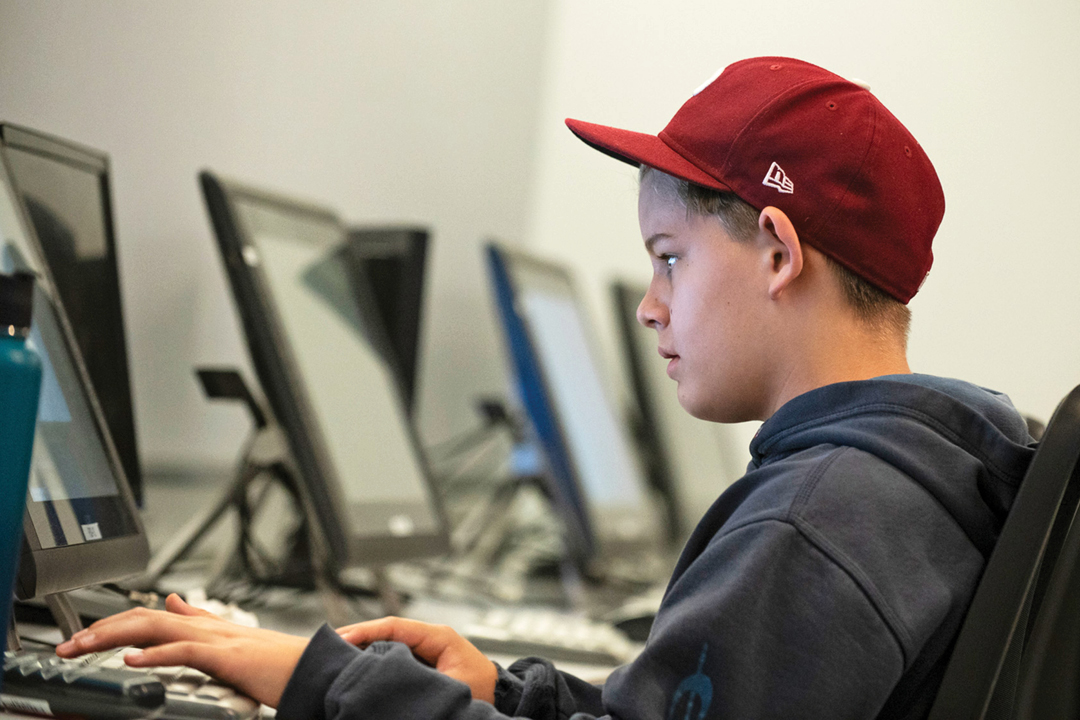 Student wearing a red hat working on a digital art project
