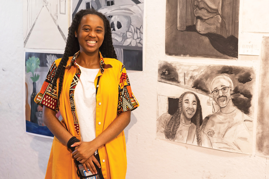 Student posing with their artwork during the final exhibition