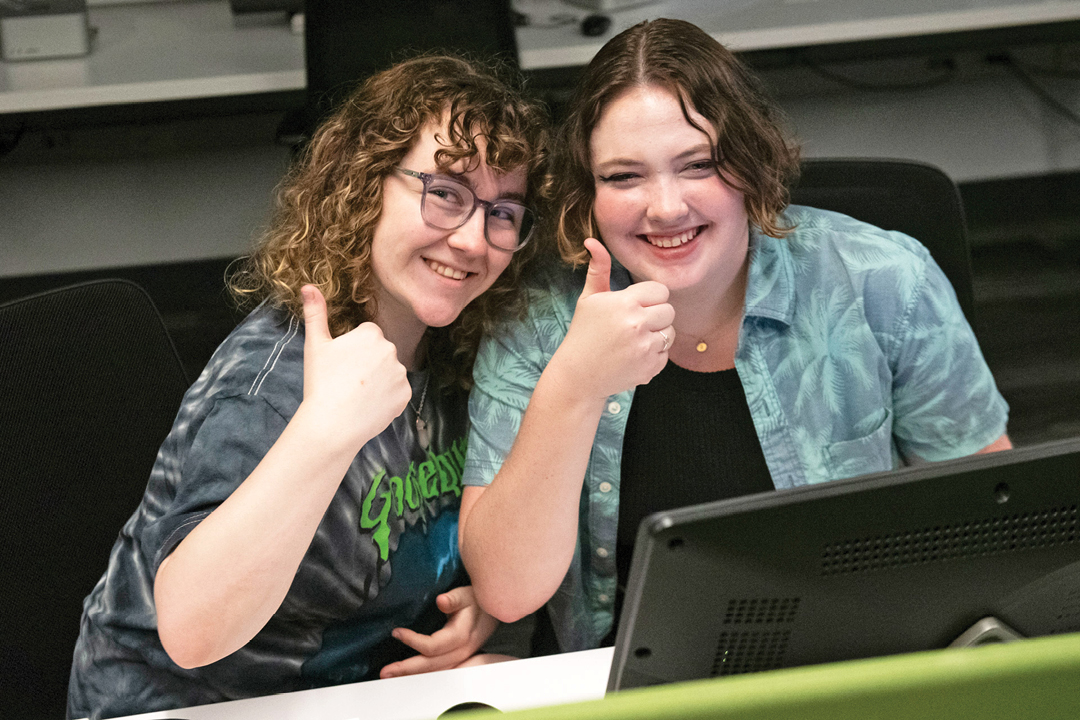 2 students giving a thumbs up and smiling
