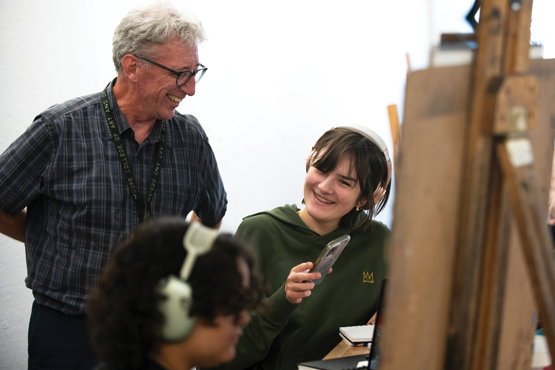 Professor and student smiling while discussing artwork